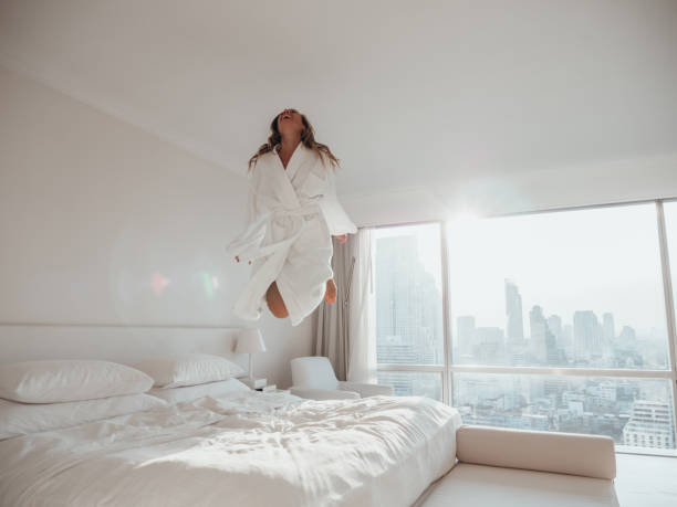 istock Woman jumping on bed in hotel room 1270763723