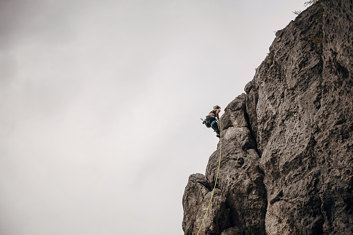 One woman, female rock climber is climbing on rocks in nature.
