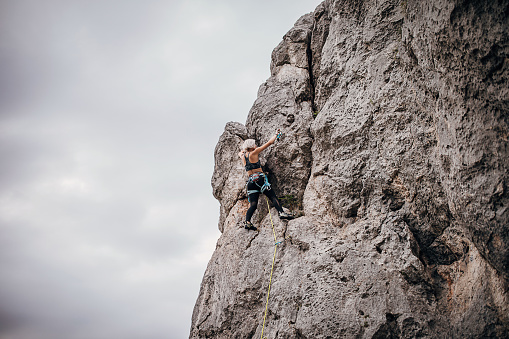 One woman, female rock climber is climbing on rocks in nature.