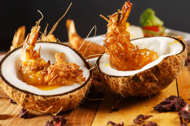 Breaded shrimp with Coconut shell in Jamaican sauce, accompanied by steamed rice and garnished with pumpkin and carrot vegetables.