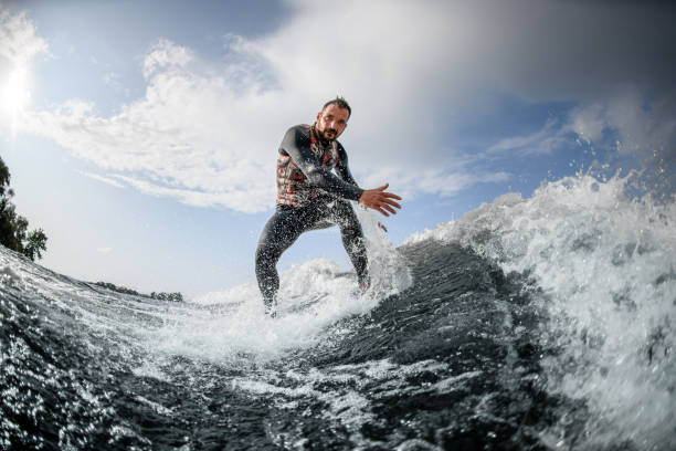 istock athletic man rides on surfboard down a wave and touches the water 1270765515
