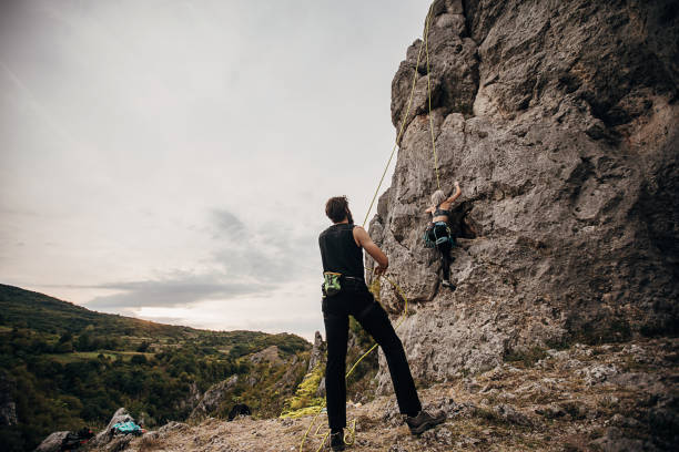 istock Woman climbing on rocks while man is assisting him by holding the rope 1270765788