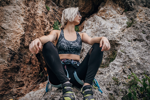 One woman, female rock climber sitting on a rock before climbing.