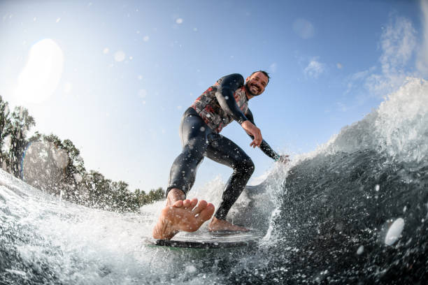 istock happy man having fun rides wave on surfboard and touches the water 1270767707
