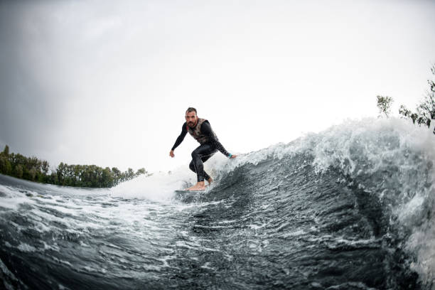 istock guy rides on surfboard down wave and touches the water 1270768889