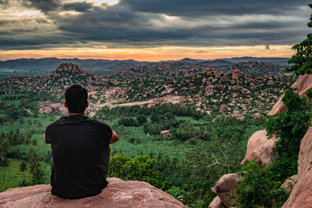 istock man sitting at mountain top watching the sunrise with dramatic sky at morning flat angle shot 1270775257