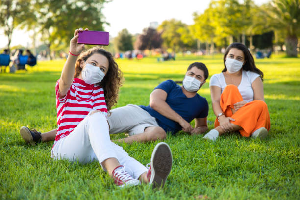 istock Three friends sitting on the grass and taking a selfie 1270776074