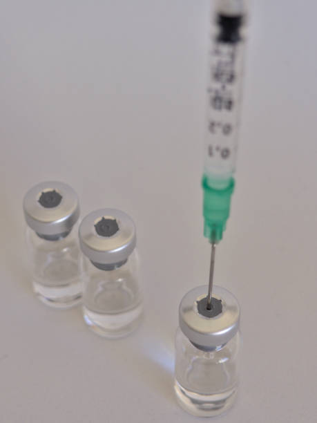 Vaccine bottles and syringe with injection fluid and aluminium caps_Green syringe Vaccine bottles and syringe with injection fluid and aluminium caps_Green syringe crista ampullaris photos stock pictures, royalty-free photos & images