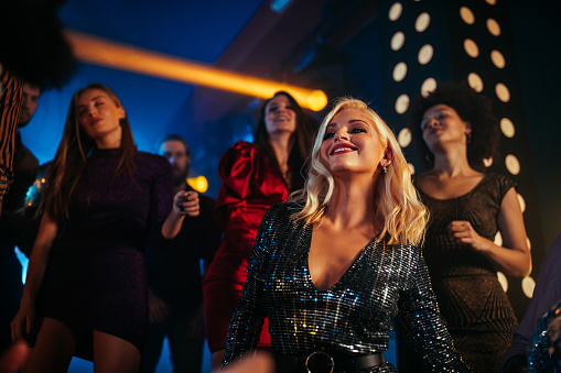 Group of young friends dancing together in the nightclub