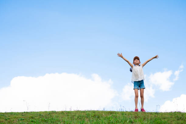 istock Child raising arms in the meadow 1270783909