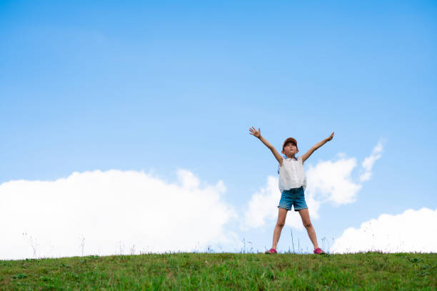 Child raising arms in the meadow