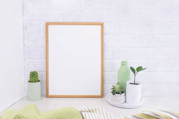 istock Empty picture mockup with wooden frame on white brick wall background with succulents plants and green vase. Light interior 1270787948