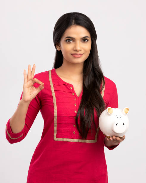 young woman saves money in piggy bank - women savings uk coin imagens e fotografias de stock