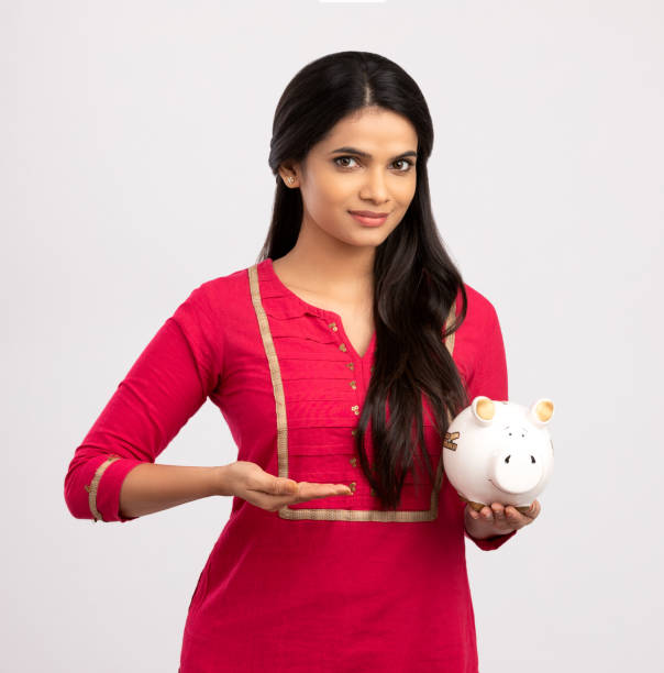 young woman saves money in piggy bank - women savings uk coin imagens e fotografias de stock