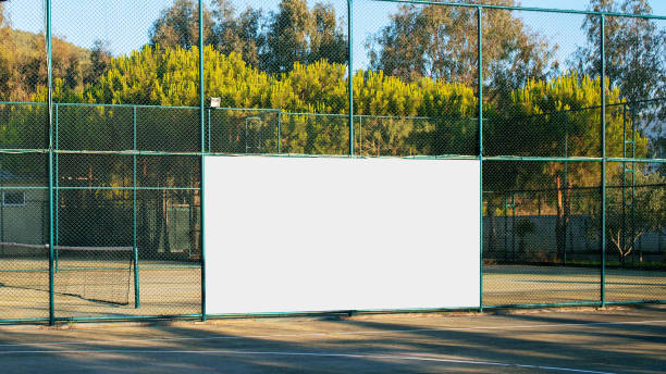 empty advertising white banner with mockup on iron fence on sport playground empty advertising white banner with mockup on iron fence on sport playground front view stadium advertising stock pictures, royalty-free photos & images