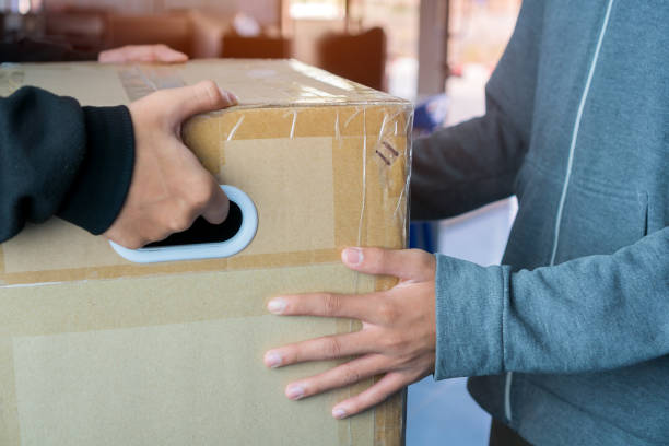 istock Messenger or deliveryman carry on parcel box package to deliver customer at home. Delivery service courier, Detail for delivery man carrying cardboard from Online shipping  courier 1270793373
