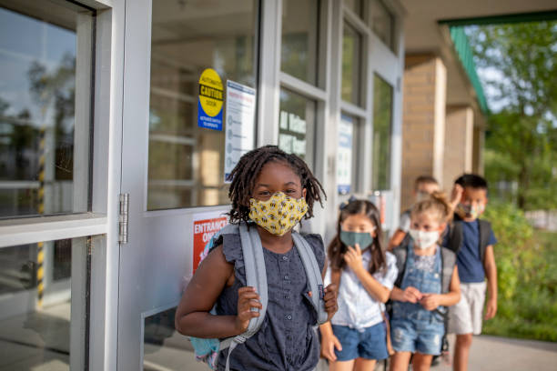 Diverse group of elementary school kids go back to school wearing masks Group of kids return to school during the pandemic. school children stock pictures, royalty-free photos & images