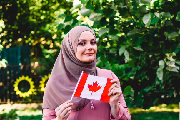 Muslim woman in hijab holds flag of Canada woman with flag citizenship photos stock pictures, royalty-free photos & images