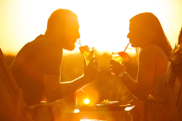 jeune couple appréciant le coucher du soleil avec des cocktails - floatation device flash photos et images de collection