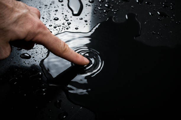 water on the surface, puddle of water water on the surface, hand touches water on a black background water on black surface stock pictures, royalty-free photos & images