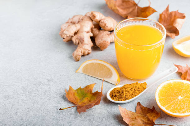 istock Immune boosting drink with citrus fruits, ginger, turmeric. Drink or smoothie with yellow fall leaves for autumn or virus season on neutral beige background 1270800445