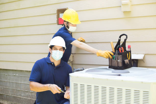 Two air conditioner workers service outside unit. stock photo