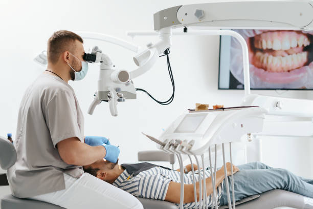 istock Male dentist wearing mask looking in the microscope 1270807631