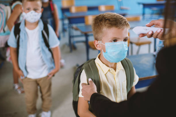 istock Female teacher using thermometer temperature screening for boy student 1270811239