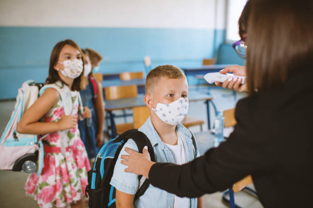 istock Female teacher using thermometer temperature screening for boy student 1270811565