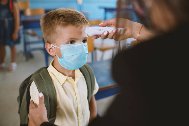 istock Female teacher using thermometer temperature screening for boy student 1270812594