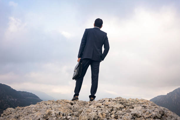 istock Young businessman on top mountain peak over clouds. 1270813020