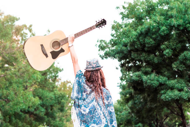 Modern woman in a hat holding a guitar in one hand. stock photo