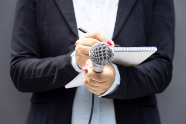istock Journalist at news conference or media event, writing notes, holding microphone 1270815944