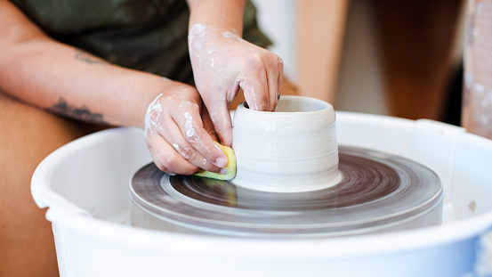 Studio ceramic workshop stock photos of a woman working with clay on the spinning wheel. Shot using all natural light.