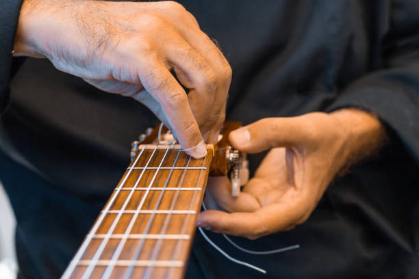 istock Male hands changing the strings of a classical guitar 1270819368
