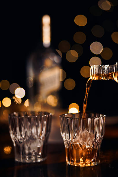 vista ravvicinata bevanda alcolica versando dalla bottiglia al bicchiere - whisky alcohol pouring glass foto e immagini stock