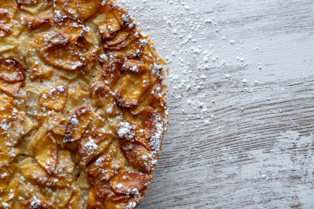 istock Homemade baking. Freshly baked apple pie on a light wooden background sprinkled with icing sugar. 1270823129