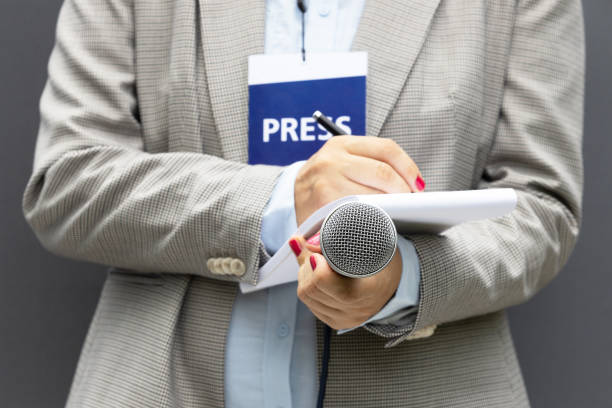 istock Journalist at news conference or media event, writing notes, holding microphone 1270825680