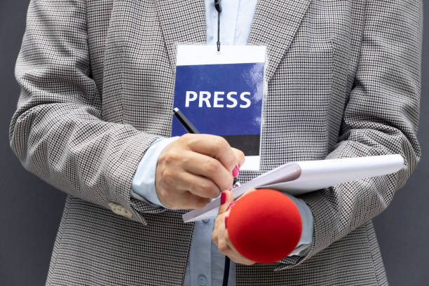 istock Female journalist at press conference or media event, writing notes, holding microphone 1270827134