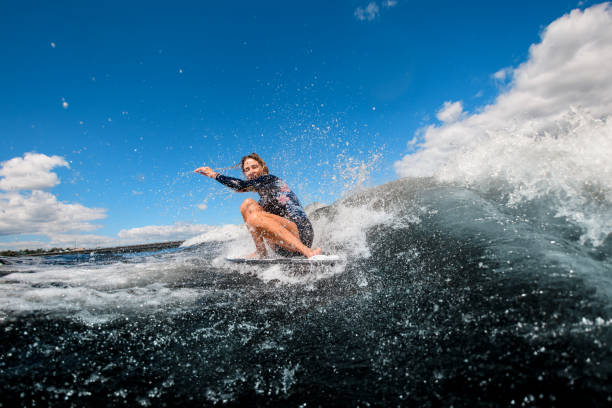 istock young woman sitting on surfboard and riding wave 1270827211