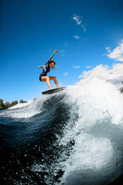 istock cheerful young woman skillfully jumping with surf board on wave 1270828285