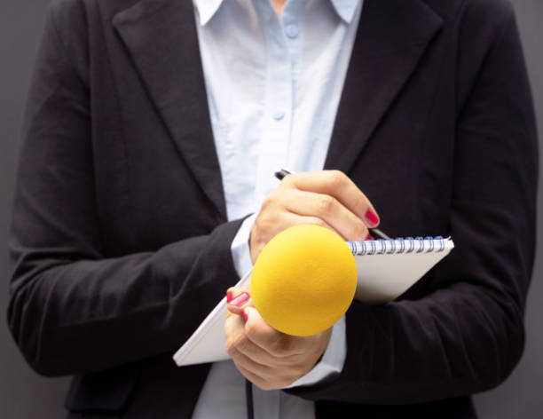 istock Female journalist at news conference, writing notes, holding microphone 1270829845