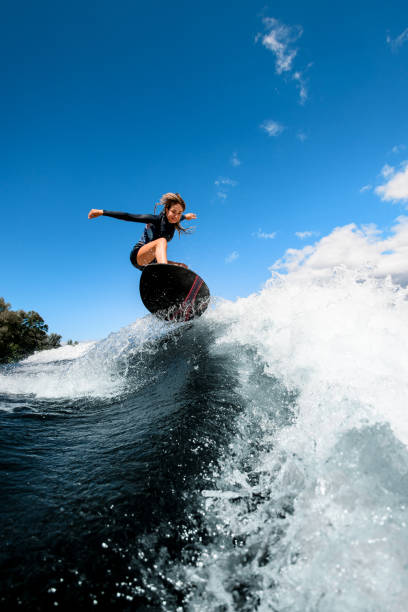 istock Handsome smiling woman skillfully jumping with surf board on wave 1270830635