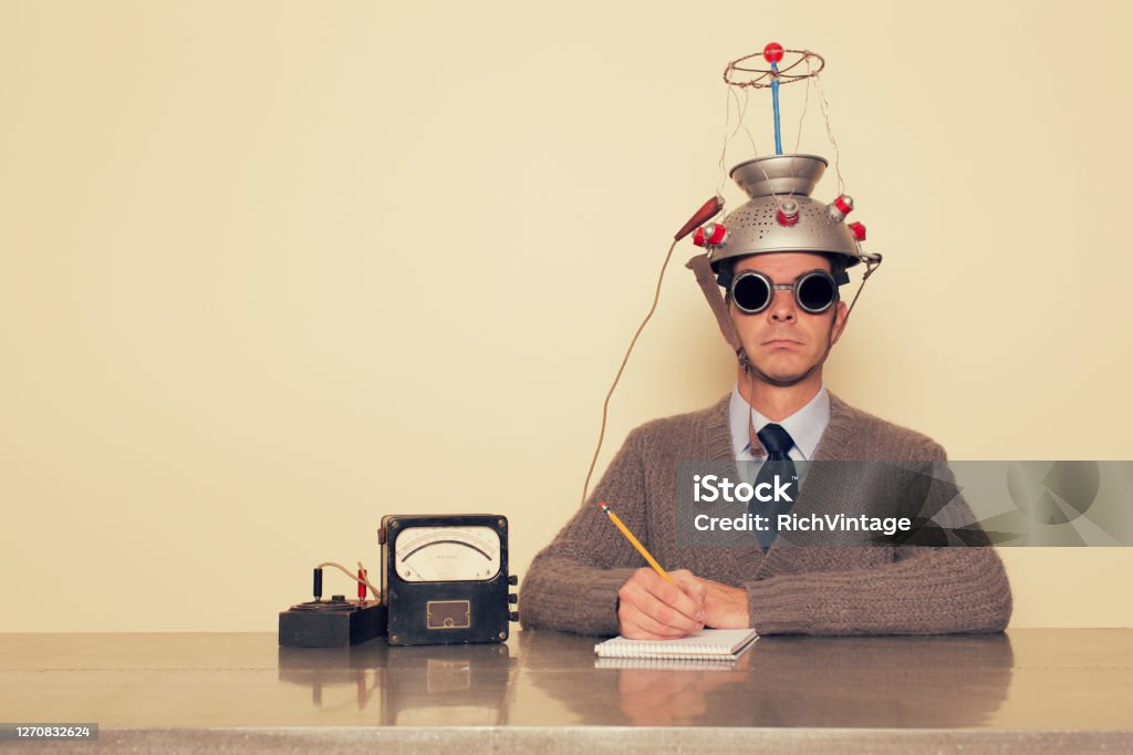 Electro Therapy Man A man is testing the limits of the mind by placing a mind reading invention on his head trying to understand the brain. He is dressed in retro sweater and tie with safety goggles waiting to measure brain waves and understand the unknown. Inspiration Stock Photo