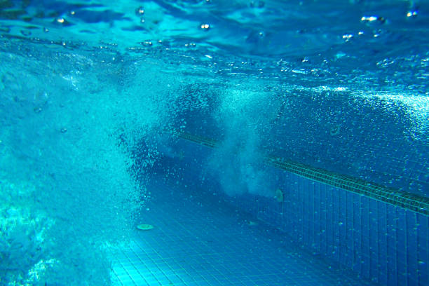 motion of water waves with splashing air bubbles. swimming pool water with aquamarine hues and light effect on a sunny day. space for copy. shooting water from activity or a slide.