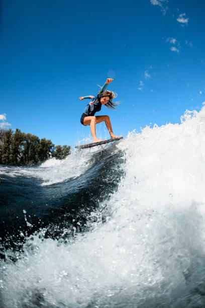 istock Beautiful young woman skillfully jumping with surf board on wave 1270834279