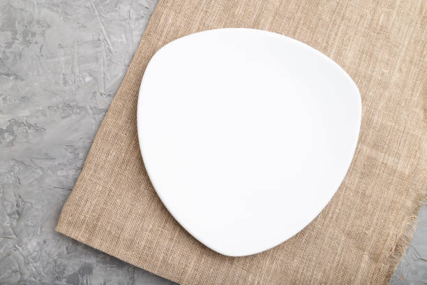 istock Empty white plate on gray concrete background and linen textile. Top view, close up, flat lay. 1270835257