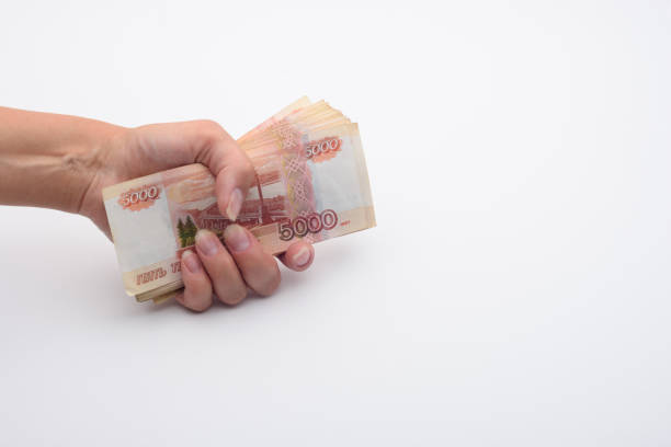 istock Hand holds a stack of five thousandth bills in a fist 1270835589