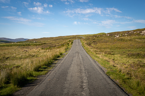Straight single track road with turns at the end in Scottish Highlands, UK. Beautiful summer sunny day