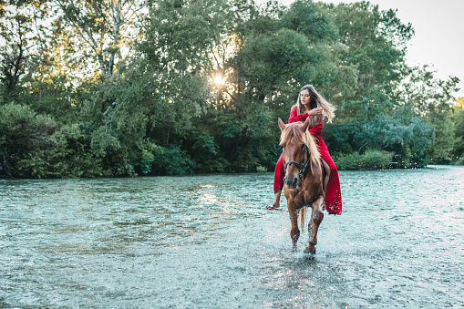 Pretty girl riding horse in river water